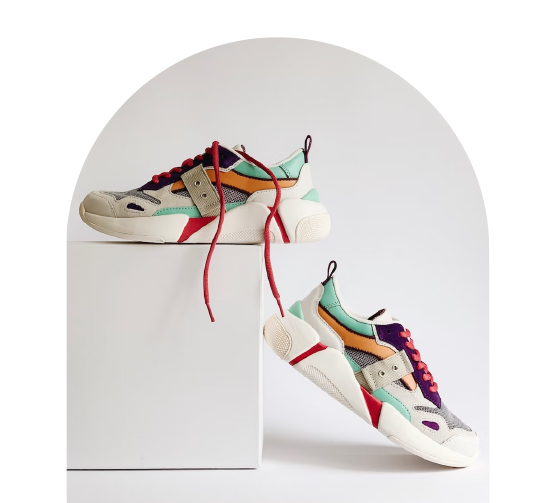 F&auml;rgglada sneakers med r&ouml;da skosn&ouml;ren, placerade p&aring; och bredvid en vit piedestal